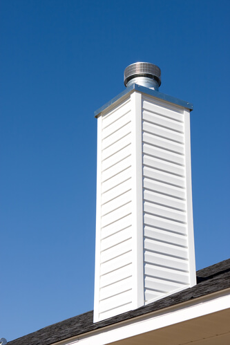 White prefabriated chimney with a metal chimney chase against a blue sky